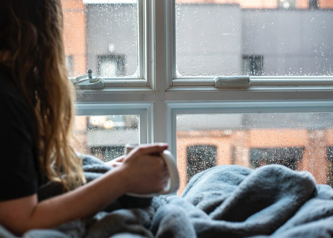 woman in gray sweater sitting beside window
